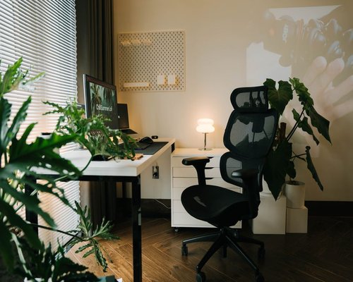A modern airy home office workspace in Monterrey with ergonomic desk chair and green potted plant on the side